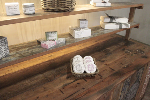 A woven basket with white soap bars placed on a recycled teak wood centre display table 207x97x80cm