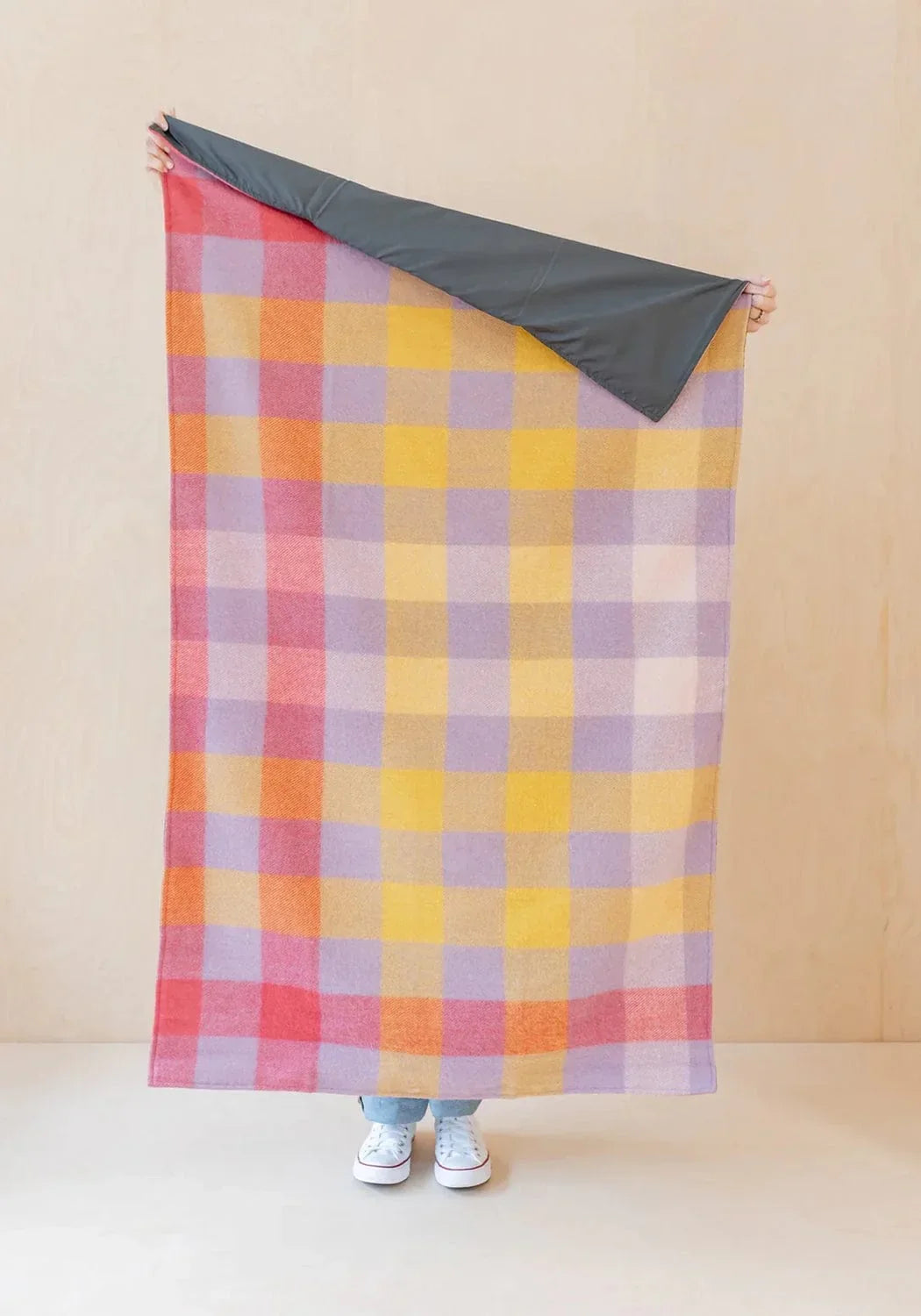 A vibrant lilac gradient gingham small picnic blanket made of recycled wool with a soft woven texture and dark gray underside