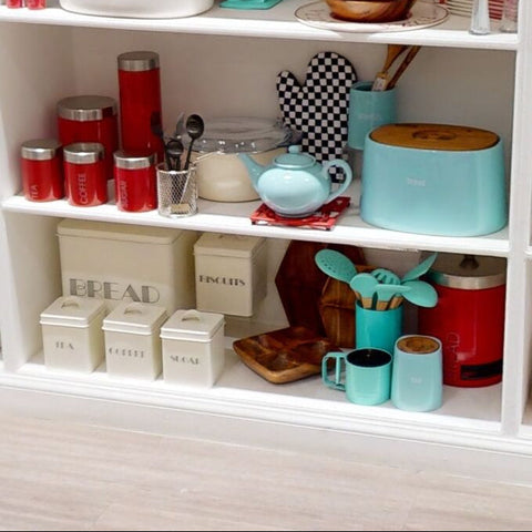 Light blue ceramic teapot with matching lid and handle on red enamel tea set red placemat