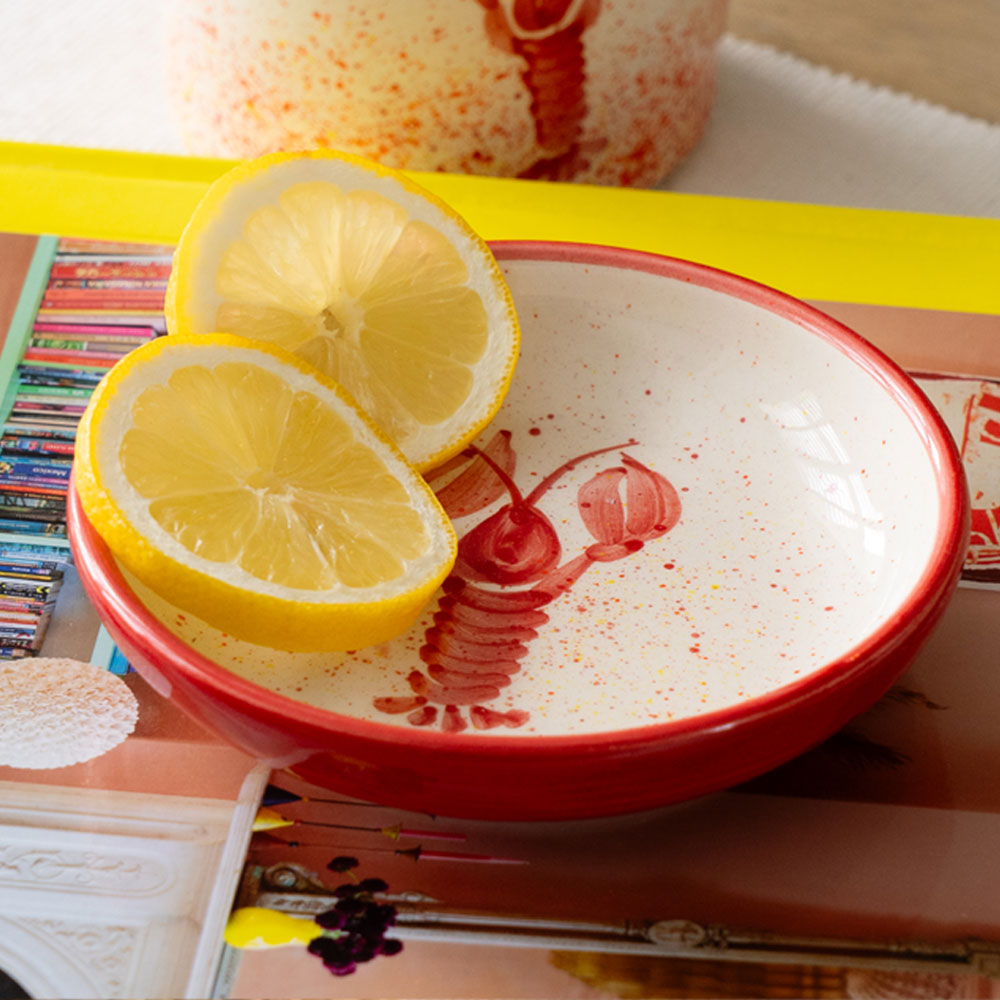 Red lobster mini ceramic dish with a white interior lobster design holding two lemon halves in a red bowl