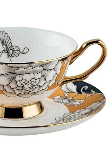 Regal bloom bone china teacup and saucer with delicate black and white floral patterns and gold trim on a warm gold background