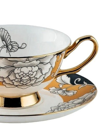 Regal bloom bone china teacup and saucer with delicate black and white floral patterns and gold trim on a warm gold background