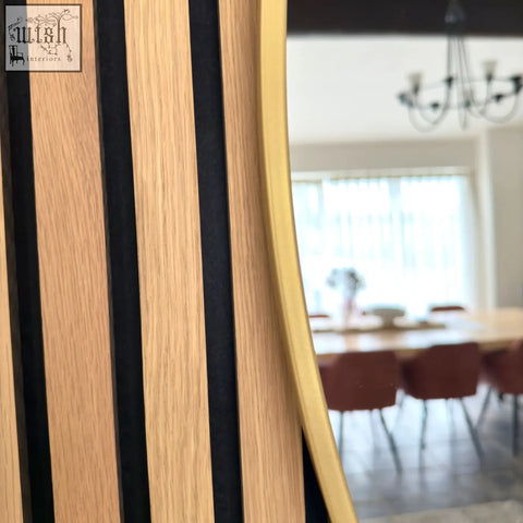 A rei 150cm gold extra large round metal circle mirror with satin gold frame reflects a dining area on wood panel wall