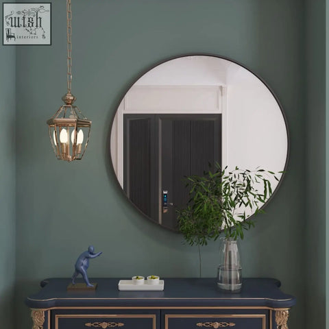 Rei 90cm black metal round wall mirror with large black frame hanging on a green wall