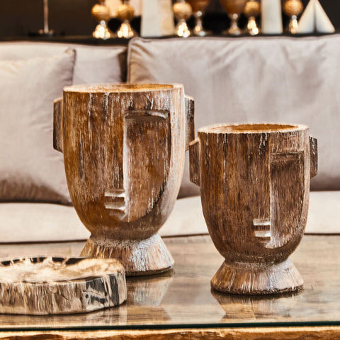 Two rustic wooden face sculptures with carved geometric features in weathered brown tones for relic petrified wood bowl