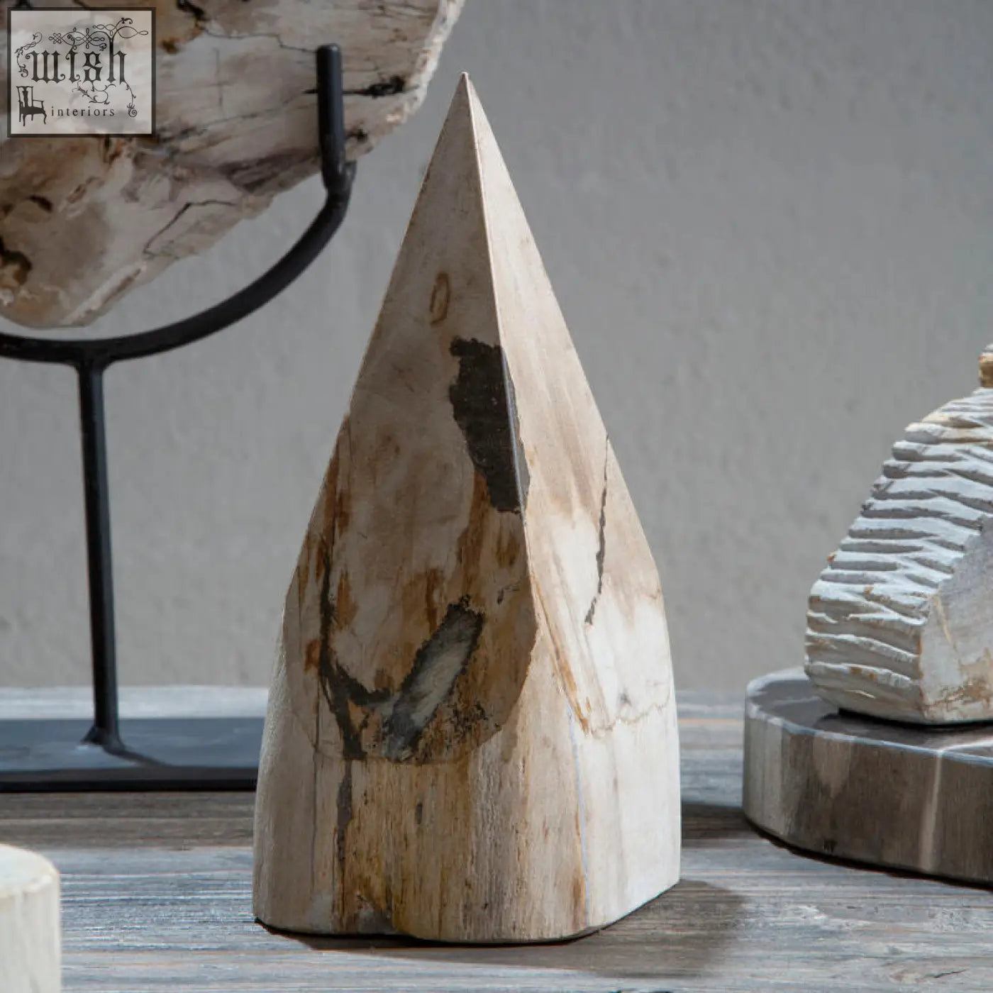 A light-colored wood pyramid sculpture with natural texture and darkened patches made from petrified wood