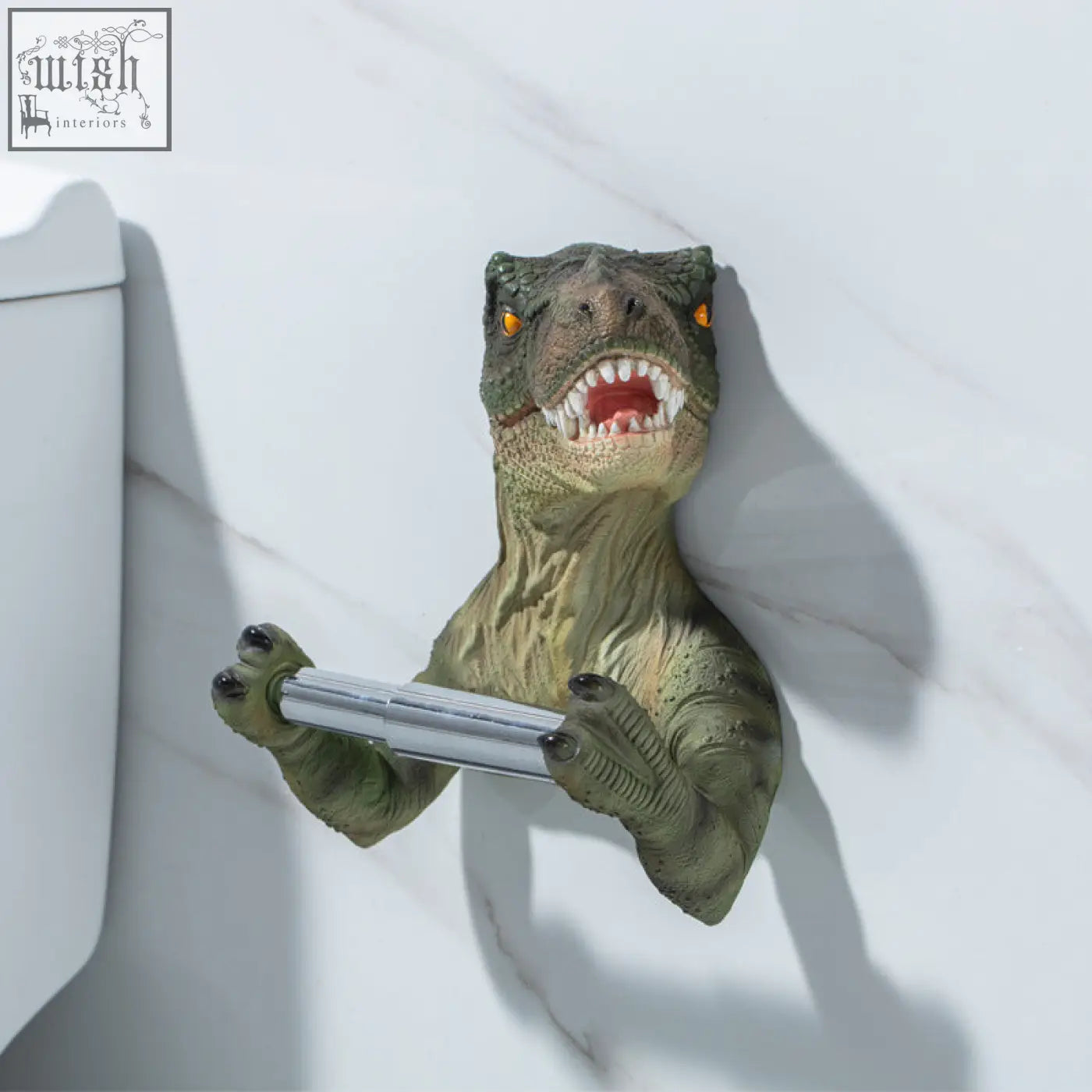 Green resin dinosaur tissue holder with orange eyes and toothy grin holding silver rod paper towel holder for bathroom