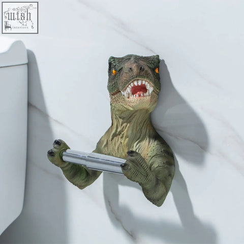 Green resin dinosaur tissue holder with orange eyes and toothy grin holding silver rod paper towel holder for bathroom