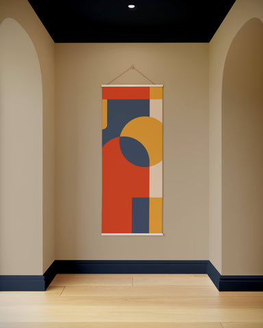 A retro geometric tapestry with bold red, orange, yellow, and navy shapes on a cream abstract wall hanging