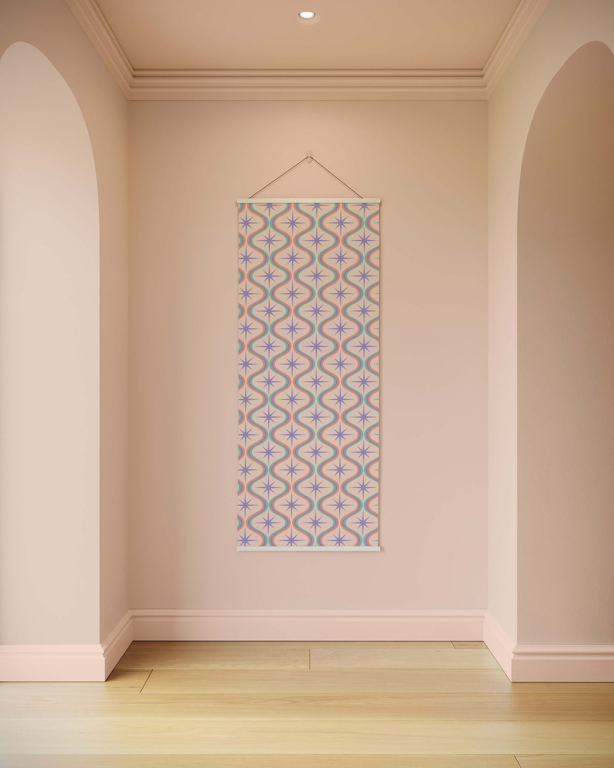 A retro pastel tapestry with a soft lavender and muted teal starburst pattern on beige hanging by a thin string