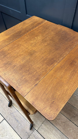 A vintage mid century wooden drop leaf table with medium brown finish and visible grain patterns for serving use