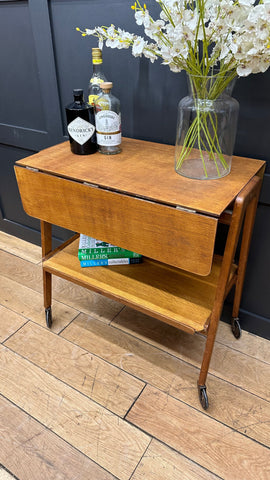 Warm-toned wooden mid century drop-leaf serving cart with lower shelf and casters perfect for tea cake or cocktails