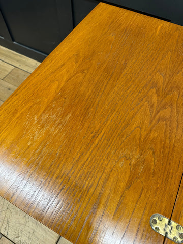 Polished golden-brown teak mid century trolley with visible wood grain and brass hinge for serving tea or cocktails
