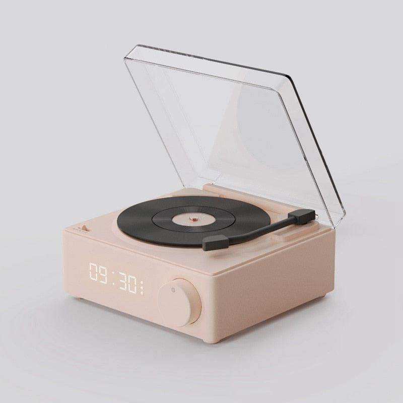 Pastel pink wireless bluetooth speaker shaped like a square digital record player with black vinyl disc and transparent lid