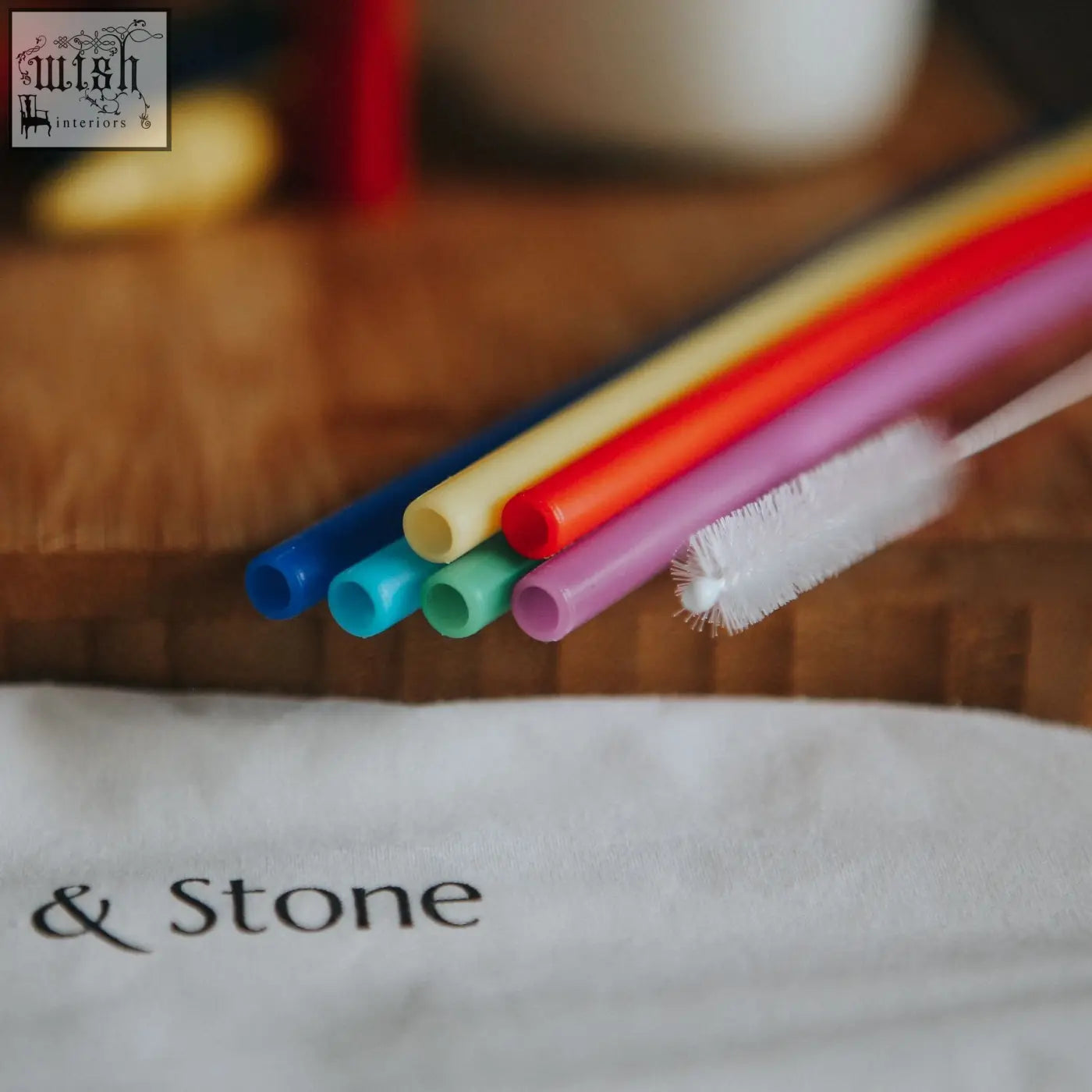 A set of colorful translucent silicone drinking straws in six colors with a white cleaning brush included