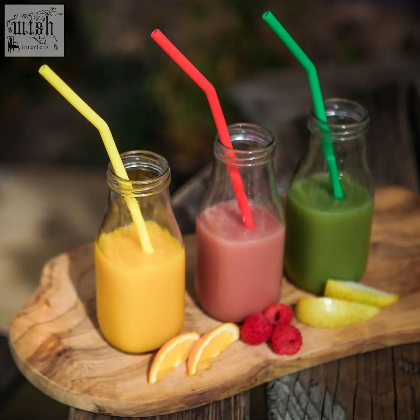 Three glass bottles with colorful smoothies and bright bendy silicone drinking straws from a 6 pack set
