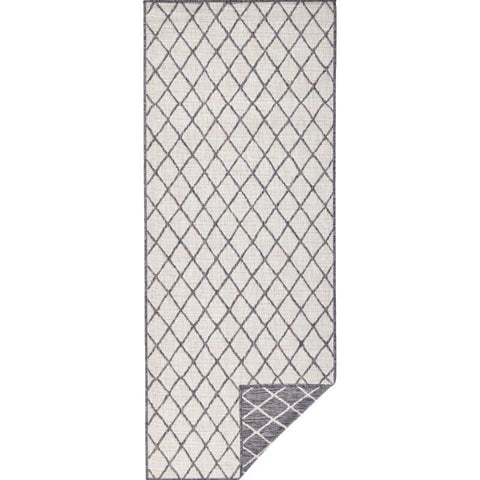 A reversible indoor outdoor flatweave rug with a subtle gray diamond lattice pattern on off white background