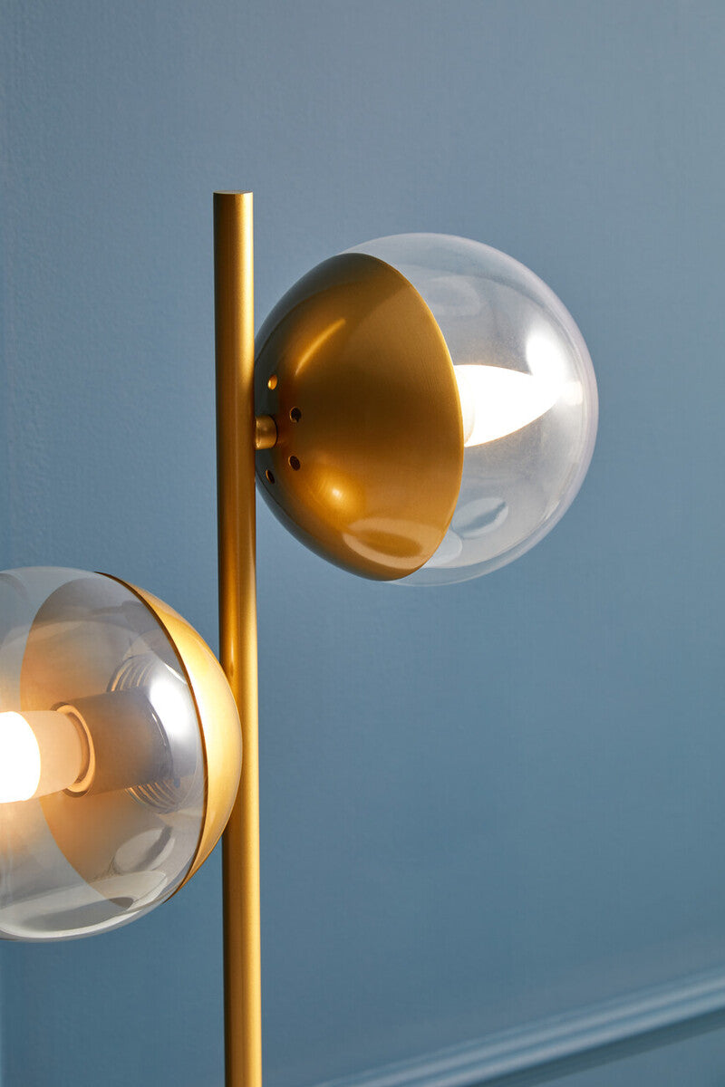 Gold-finished two light gold floor lamp with black marble table base and dual spherical glass shades