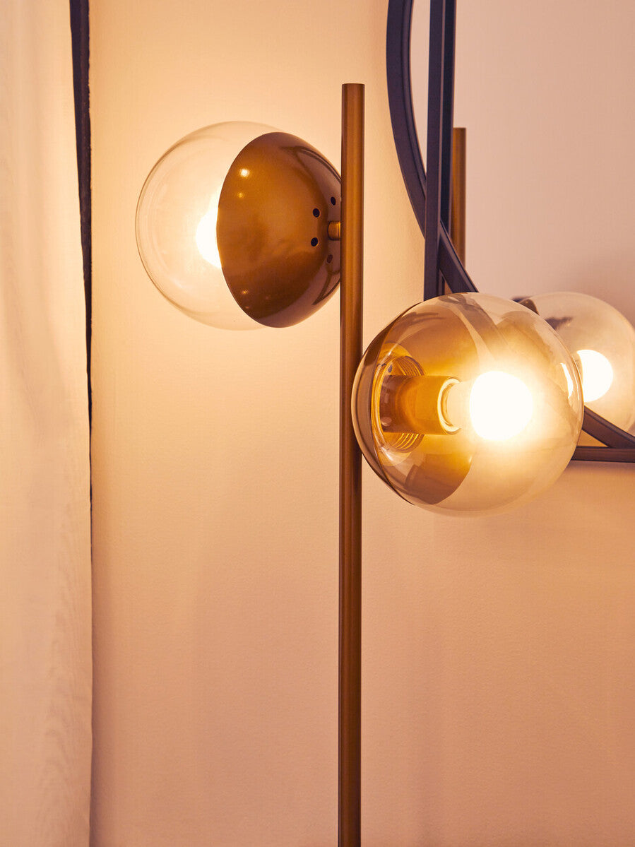 Modern brass finished floor lamp with three glass globes and curved arms in black marble table base design