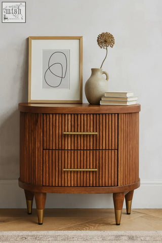 Curved wooden bedside table in solid mango wood with amber oak finish two ribbed-front drawers and brass accents