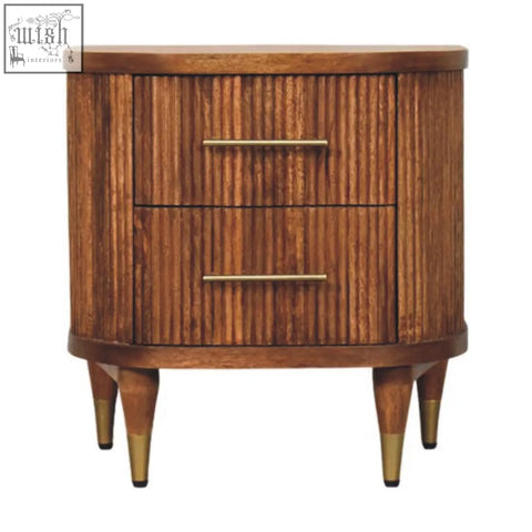 A mid-century modern nightstand in solid mango wood with an amber oak finish and two ribbed-front drawers with brass handles