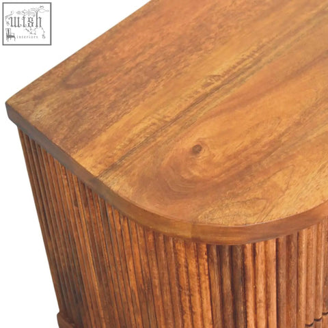 Warm-toned ribbed bedside table with two ribbed-front drawers in solid mango wood and amber oak finish
