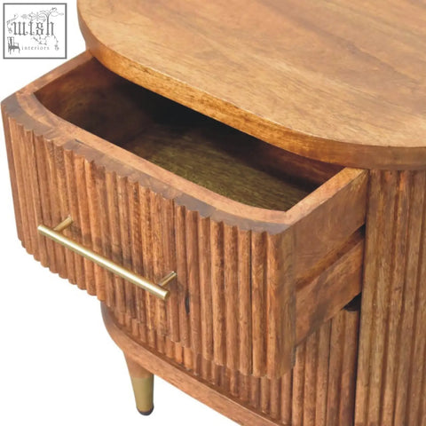 A warm-toned bedside table in amber oak finish with two ribbed-front drawers made of solid mango wood and brass accents