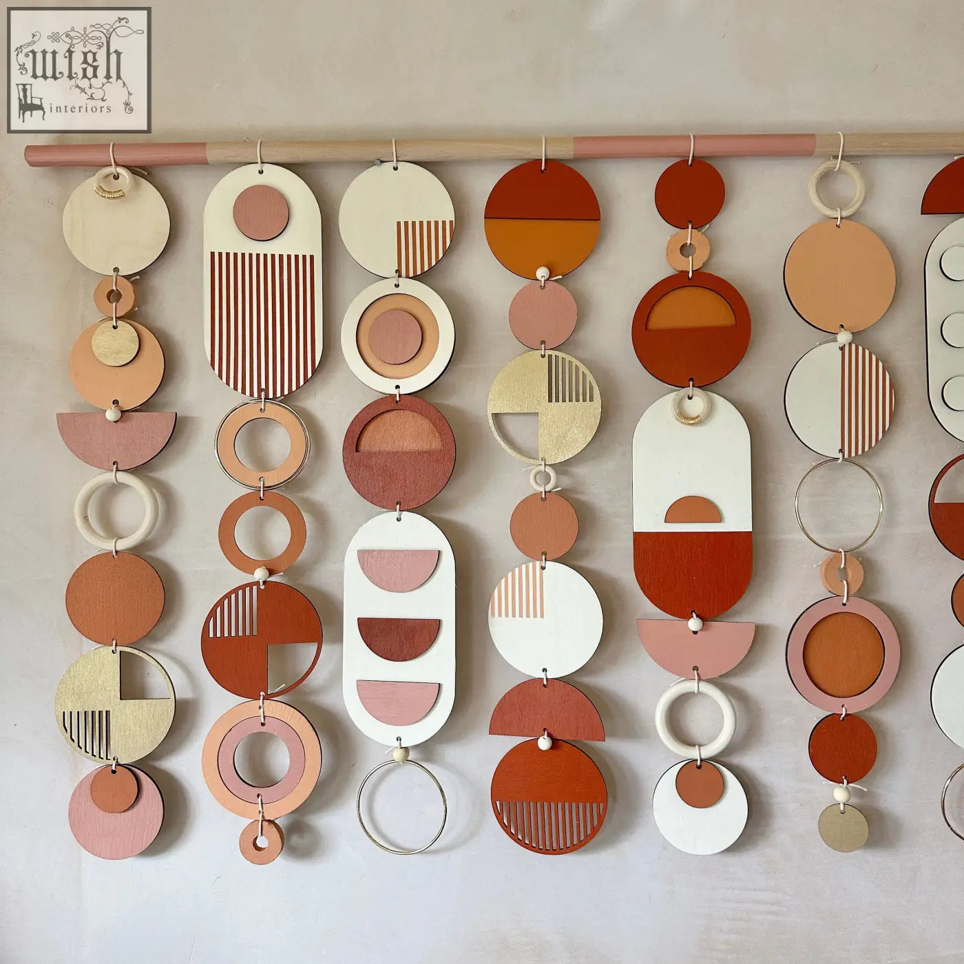 A modern geometric wall hanging with layered wooden discs in warm colour palette terracotta cream and beige for home decor