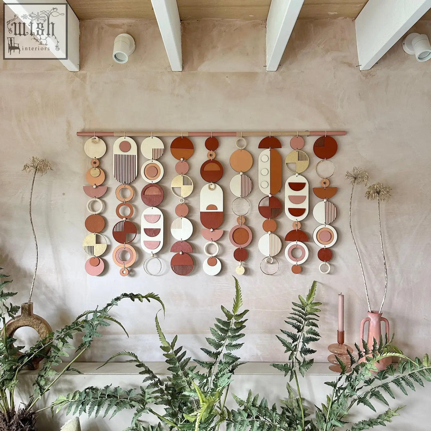 A modern geometric wall hanging with layered wooden circles in a warm colour palette perfect for home decor