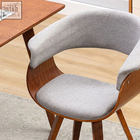 Gray upholstered richie dining chair with curved wooden frame and tapered legs perfect for dining areas