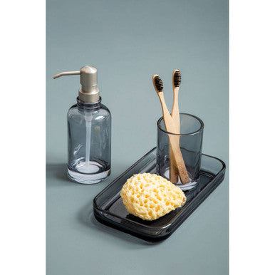 Dark gray glass soap dispenser with metallic pump top shown with ridley glass tumbler product