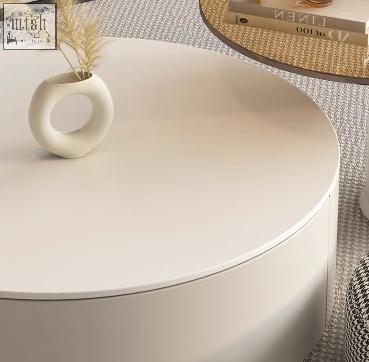 Cream-colored ceramic vase with ring-shaped design on a riviera round nesting coffee table set with ottoman white