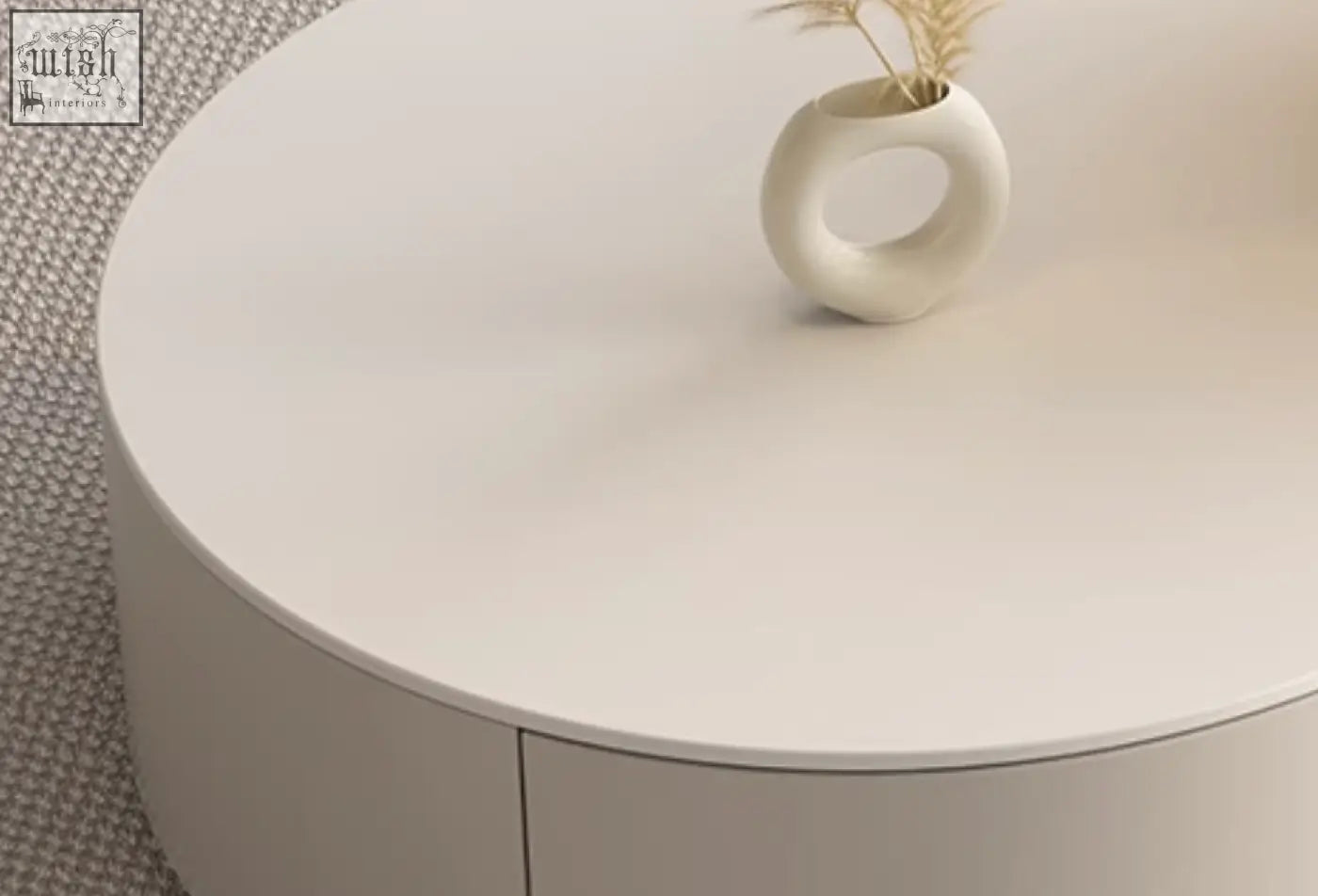A minimalist white ceramic vase with a ring handle and dried grasses on a riviera round nesting coffee table set