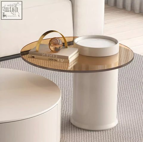 A sleek riviera round nesting coffee table with a transparent glass top and a white cylindrical base