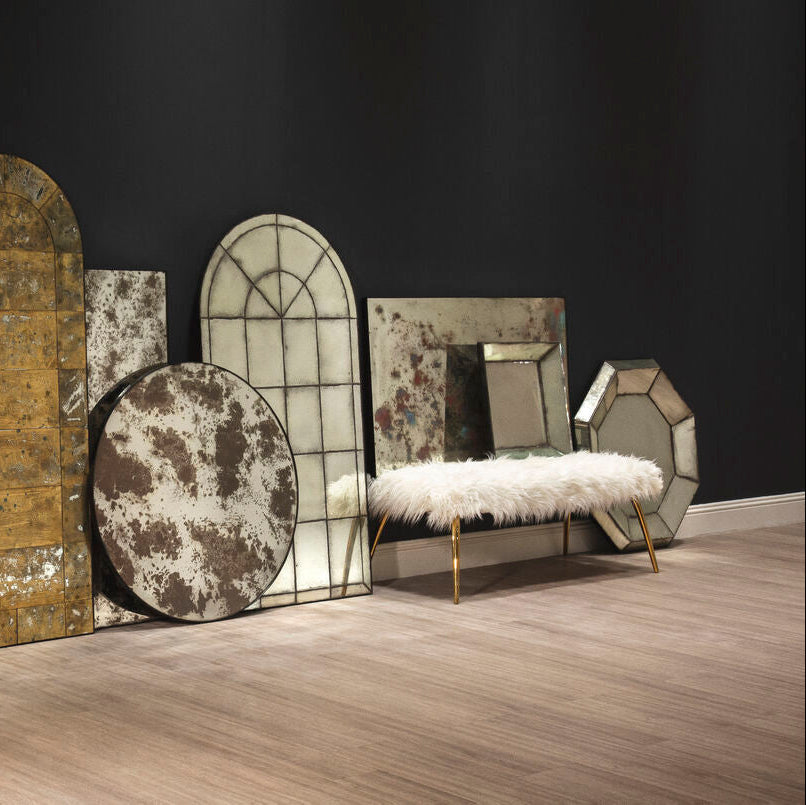 A plush white fur bench with slender gold legs paired with a modern octagonal wall mirror for stylish decor