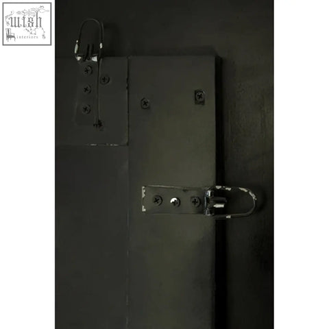 Black metal door with heavy-duty latches and bolts on the back of riza large panelled wall mirror panelled wall design