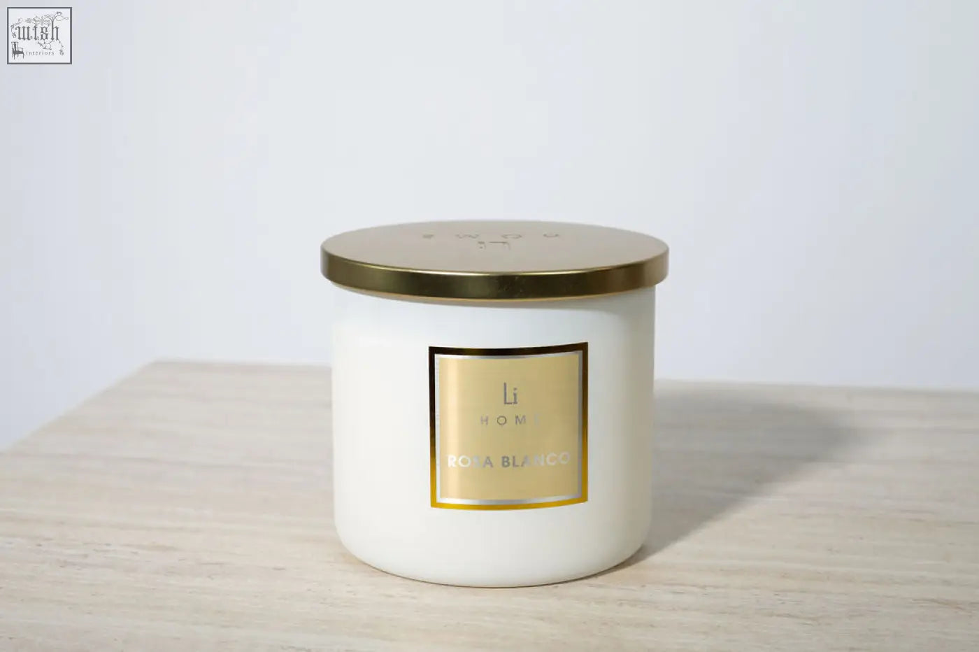 A white cylindrical large candle with gold lid and li home rosa blanca label from a luxury candle collection