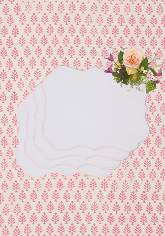 A delicate white scalloped paper note card with a soft peach rose and purple accents on rosa pink placemats set of 4