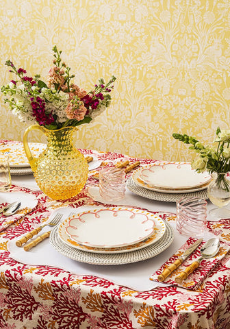A vibrant yellow textured glass pitcher with colorful flowers next to rosa pink placemats set of 4