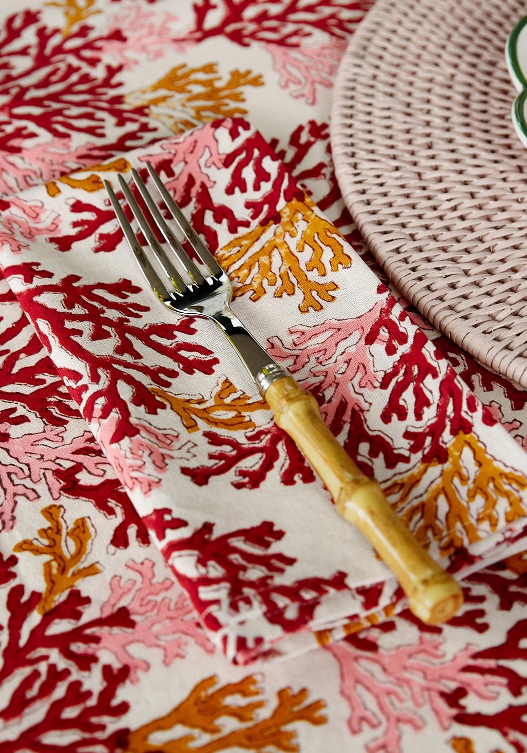 A fork with bamboo handle on a coral pattern rose coral table napkin set of 4 perfect for dining use