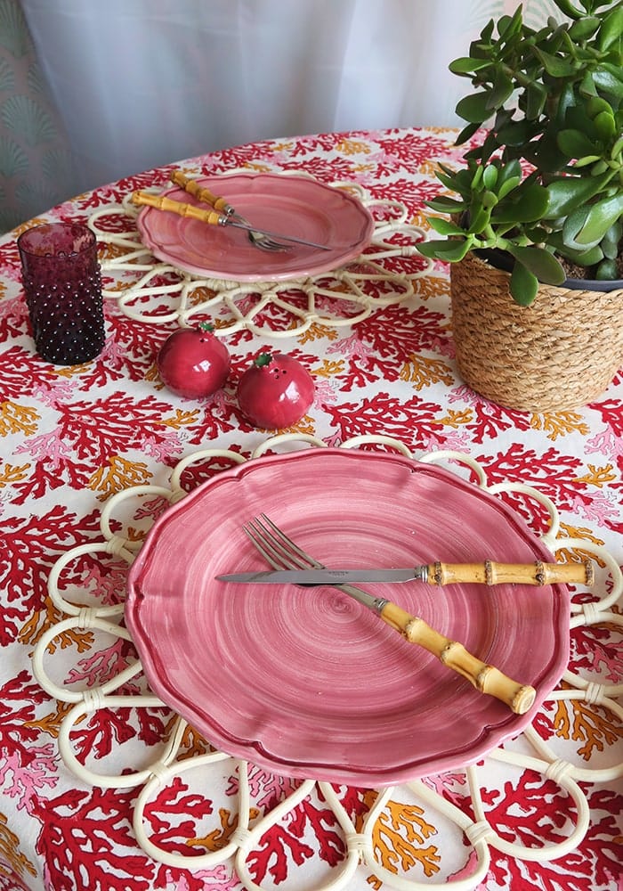 Pink ceramic plate with scalloped edge and circular ridges paired with rose coral tablecloth for stylish dining