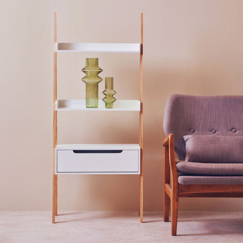 Modern wooden rostok shelf unit with white shelves and drawer holding green glass vases saves floor space