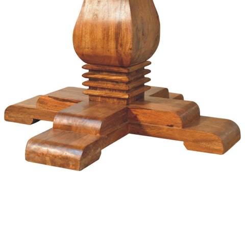 A polished medium brown wooden round pedestal dining table base with a turned column and curved x shaped legs