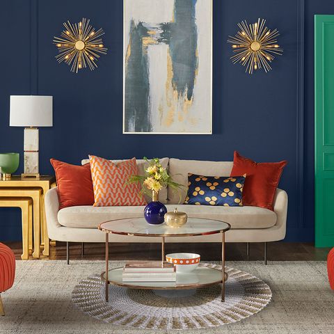 Beige sofa with orange and patterned throw pillows next to a round seagrass white and tan inner sun 1m rug