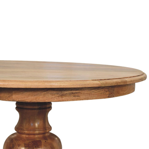 Light brown wooden round dining table with smooth polished surface and turned pedestal base