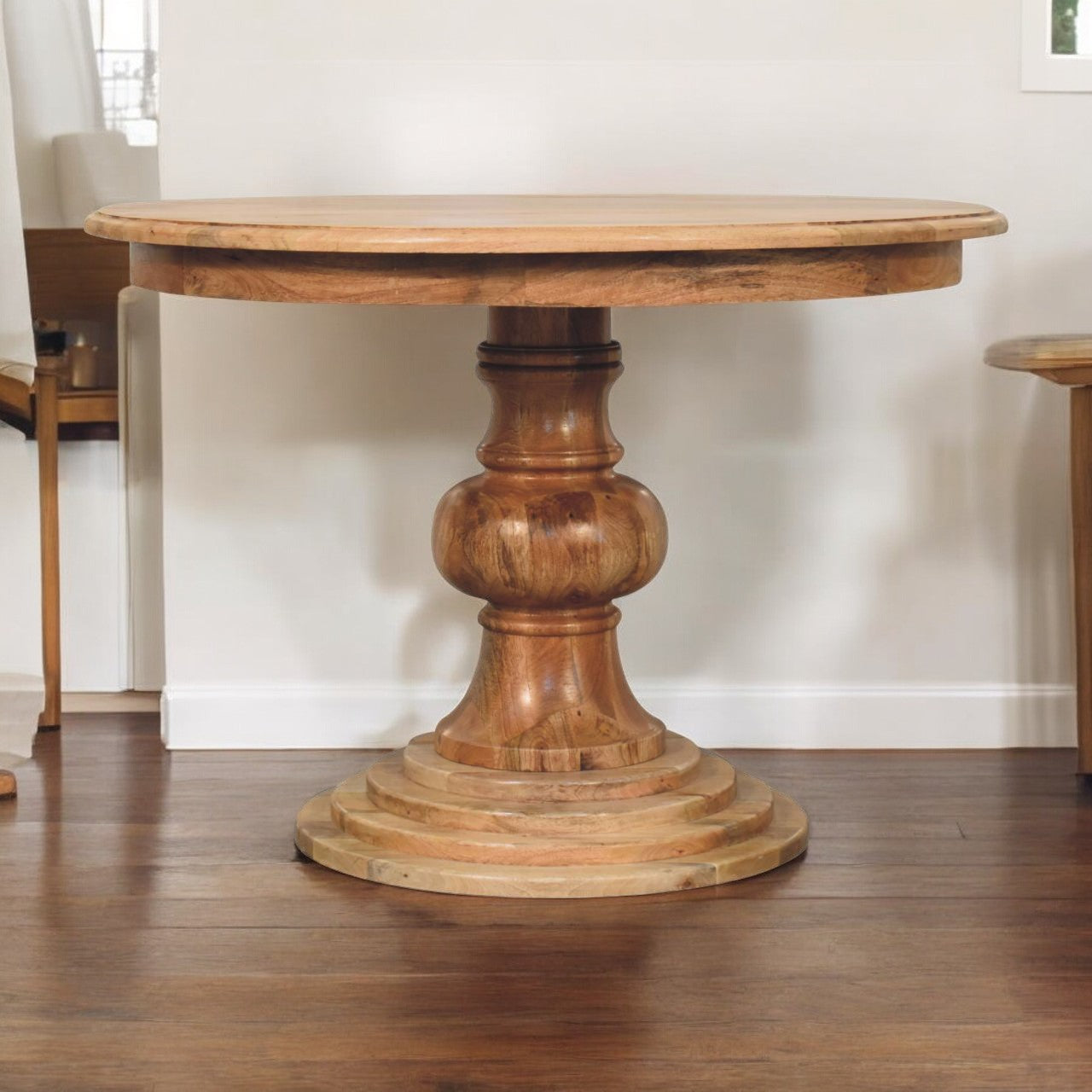 Rustic round turned dining table with thick natural wood finish and ornate stacked circular pedestal base