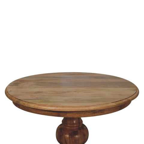 Round turned dining table with a natural finish and visible wood grain made of round wooden pedestal material