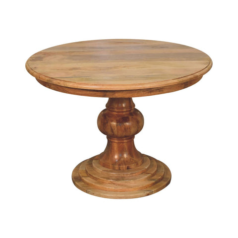 Round turned dining table with a warm natural finish and an intricately carved wooden pedestal base