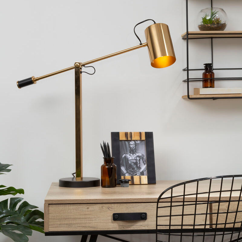 Brass-finished adjustable desk lamp with black base and cord displayed next to rova 5 x 7 photo frame