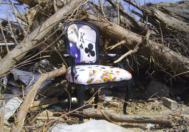 Royal flush poker chair with black frame and white seat cushion featuring playing card designs, likely made of upholstered fabric.